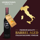 A bottle of Georgetown Olive Oil Co. Tangerine Balsamic Vinegar, featuring a tangerine tag and gold Italy map graphics set against a burgundy and olive backdrop. The text emphasizes premium quality and authentic Italian origin, highlighting this exquisite aged balsamic vinegar from Modena, Italy, infused with bright tangerine notes.