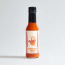 A bottle of Culture Hot Sauce Tangerine Dream by Culture Hot Sauce, featuring bright orange sauce, stands upright against a plain white background—an eye-catching citrus hot sauce that adds zesty brightness to any dish.