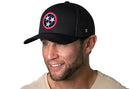 A man with a neatly trimmed beard, wearing the Haka Hat Tennessee Flag Trucker Hat—Black TN Snapback—smiles in a light beige shirt while looking slightly to the side.