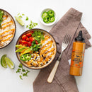 Two bowls of rice topped with smoky chipotle sauce, black beans, tomatoes, avocado, jalapeños, cilantro, and lime wedges. A fork, napkin, and a Terrapin Ridge Farms Spicy Chipotle Garnishing Squeeze bottle sit beside them for extra flavor.