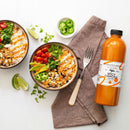 Two rice bowls with veggies, black beans, jalapeños, tomatoes, and drizzled with Terrapin Ridge Farms Spicy Chipotle Garnishing Aioli. Nearby are a beige napkin with a fork, lime wedges, sliced jalapeños, and the aioli bottle.