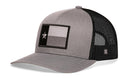 The Haka Hat Texas Flag Trucker Hat features a gray front, black mesh back, and a patch with a stylized black, gray, and white Texas flag and single star. Shop the Gray-Black TX Snapback by Haka Hat.