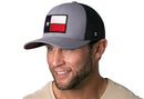 A smiling man wears the Haka Hat Texas Flag Trucker Hat, a gray-black TX snapback with a front patch by Haka Hat, paired with a light shirt against a white background.