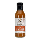 A glass bottle of B.T. Leigh’s Mustard Maple Rosemary BBQ Sauce with a white label featuring a bearded man logo, an award-winning badge, and the text The Clevelander.