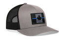 The Haka Hat Thin Blue Line Trucker Hat is a gray-black snapback featuring a tactical embroidered patch with a grayscale Canadian flag and blue line behind a black maple leaf on the front.