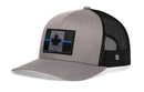 The Haka Hat Thin Blue Line Trucker Hat is a gray-black snapback featuring a mesh back and Canadian maple leaf patch with a bold blue line, combining tactical style and comfort.