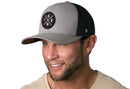 Smiling man with short brown hair and trimmed beard wears a beige shirt and a Haka Hat Toronto Trucker Hat—Gray-Black TOR X Snapback—with a circular TOR logo and maple leaf.