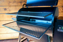 Two Pimp My Grill® Gen2 Slide-Out Rack System metal grill grates pulled out from the open lid of a pellet grill to expand cooking capacity.