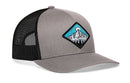 The Haka Hat Diamond Mountain and Trees Trucker Hat is a gray-black outdoors snapback with a mesh back and a front patch showing a stylized mountain, blue sky, and sun.