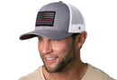 Man wearing the Haka Hat Thin Red Line Trucker Hat, a gray-white fire tactical snapback by Haka Hat, featuring a black and red American flag patch and white mesh back.