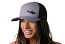 A woman wears the Haka Hat Shark Trucker Hat, a stylish gray-black beach snapback featuring a bold black shark logo and H emblem from Haka Hat.