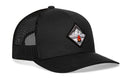 The Haka Hat Campfire Trucker Hat in black is a mesh snapback with a curved bill and features a diamond-shaped embroidered mountain and campfire patch—ideal for your next outdoor adventure.
