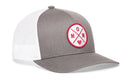 The Haka Hat Mom Trucker Hat is a gray and white snapback with a mesh back and comfort-fit sweatband. A round front patch shows "MOM" in red letters with a red heart inside a white circle. Brand: Haka Hat.
