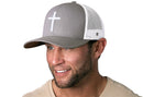 A smiling man wears a Haka Hat Cross Trucker Hat—gray and white snapback with a bold cross on the front—and a light beige T-shirt.