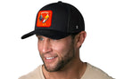 A man wears the Haka Hat Rooster Energy Trucker Hat, a black snapback featuring an embroidered rooster patch and "energy" text—stylish headwear by Haka Hat.