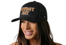 A smiling woman wears the Haka Hat Cowboy Trucker Hat, a black snapback by Haka Hat featuring bold yellow "COWBOY HAT" 3D embroidery. The comfort-fit hat stands out against a white background.