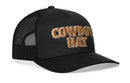 The Haka Hat Cowboy Trucker Hat is a black mesh snapback featuring bold tan and brown 3D "COWBOY HAT" embroidery on the front, designed by Haka Hat for all-day comfort.