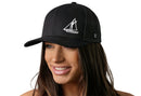 A woman with long brown hair smiles while wearing the Haka Hat Sailboat Trucker Hat, a black snapback by Haka Hat with a white sailboat graphic on the front panel, set against a plain white background.