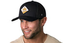 A man smiles wearing the Haka Hat Horse & Cowboy Trucker Hat, a black diamond snapback featuring a cowboy riding a horse on the front patch.