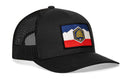 The Haka Hat Utah Flag Trucker Hat is a black mesh snapback with a curved bill, featuring a colorful hexagon patch of the Utah flag’s blue, white, and red mountain landscape on the front.