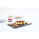 A rectangular block of cheese with Terrapin Ridge Farms Hot Pepper Bacon Jam (2oz) is served on a slate board with crackers. A jar of the jam and extra crackers appear in the background on a white surface.