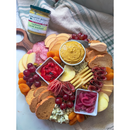 A charcuterie board with grapes, apples, blue cheese, bread crisps, cured meats, pickled onions, roasted peppers, apricots, and a bowl of creamy mustard. Terrapin Ridge Farms Raspberry Wasabi Mustard adds a sweet-spicy kick.