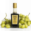A bottle of Taycte Acetaia Malpighi Gold Balsamic Vinegar of Modena — IGP Certified, Aged 15-20 Years stands in front of a bunch of green grapes on a white background.