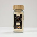 A glass jar with a wooden lid, labeled Spice Wheel Vanilla Sugar by Spice Wheel, Net Wt. 92g, containing light brown sugar infused with natural vanilla beans, is set against a plain white background.
