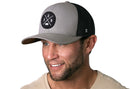 Smiling man wearing the Haka Hat Vancouver Trucker Hat—Gray Black VAN Snapback by Haka Hat, with a circular patch and comfort fit—styled casually with a beige shirt on a white background. Ideal for casual Vancouver Washington style.