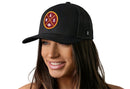 A smiling woman wears the Haka Hat Washington DC Trucker Hat, a black mesh snapback with a circular red and yellow patch showing "ASW" and a football graphic. The background is white. Brand: Haka Hat.