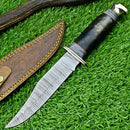 The Texan Knives Western Boulder Colorado Knife, featuring an 11" handmade Damascus steel blade, epoxy resin handle, and brass guard, rests beside its leather sheath on green grass.