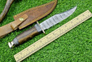 The Texan Knives Western Boulder Colorado Knife features a 13” handmade Damascus steel blade, rosewood handle, and brass guard, paired with a brown leather sheath—all displayed beside a wooden ruler for scale on green artificial grass.