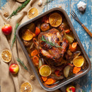 A roasted whole chicken seasoned with SALTOPIA Infused Sea Salts' POLITE POULTRY salt sits in a baking tray with potatoes, carrots, and orange slices on a rustic table surrounded by apples, dried oranges, walnuts, and garlic.