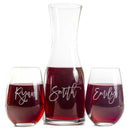 A Wine Decanter - The Script set featuring a glass decanter and two stemless wine glasses filled with red wine, each engraved with the cursive names Ryan, Smith, and Emily.
