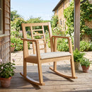 The DirectDeals Wooden Rocking Chair with Upholstered Seat and Ladder Back sits on a sunny porch surrounded by potted flowers, with a garden and house in the background.