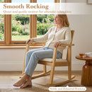 A woman relaxes on the DirectDeals Wooden Rocking Chair with Upholstered Seat and Ladder Back in a sunlit room. Enjoy smooth, stable rocking and quiet comfort—a cup of tea rests nearby.
