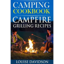 A man and a woman sit on the ground roasting food over a campfire next to a copy of Camping Cookbook: Campfire Grilling Recipes - Paperback.