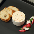 Three slices of bread, a small bowl of herbed spread infused with The Spice Lab Flavors of Provence Seasoning Set, and sliced radishes with parsley are arranged on a black plate.