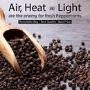 A wooden scoop with The Spice Lab Organic Black Tellicherry Peppercorns Whole spilled on a wooden surface. Text highlights that air, heat, and light can damage fresh peppercorns, and notes features: resealable bag for freshness, best quality, and best price from The Spice Lab.