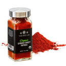A glass jar from The Spice Lab Organic Starter Spice Set—one of six included jars—labeled as organic, is displayed next to a small pile of vibrant red paprika powder on a white background.