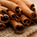 Close-up of several The Spice Lab Organic Cinnamon Sticks arranged on a piece of burlap fabric, displaying their curled ends and textured brown surfaces—perfect for adding warmth to mulled wine or chai.
