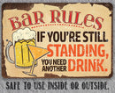 The Lone Star Art Bar Rules - Metal Sign features a beer mug and cocktail glass with the message: “If you’re still standing, you need another drink.” Safe for indoor or outdoor use.