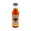 A bottle of Brushfire Farms Brushfire Glaze, adorned with an illustrated cactus and flames on the label, filled with amber-colored glaze that promises sweet heat, set against a white background.