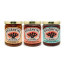 The Brushfire Farms Three Amigos gift box features three jars of Brushfire Farms pepper jam—Peach Pepper, Original Pepper, and Prickly-Pear Pepper—arranged side by side with gold lids and illustrated cactus-design labels. Ideal for any occasion, each jar can also be finished with a customized logo for a personalized touch.