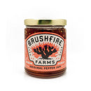 A jar of Brushfire Farms Original Pepper Jam with a gold lid features a fiery cactus illustration on the label, which notes that it’s handmade in San Antonio, Texas. This jam from Brushfire Farms brings bold, smoky heat to your table—perfect as a spicy glaze or accompaniment for your favorite dishes.
