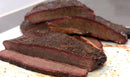 Sliced beef brisket on a white plate with a blurred background