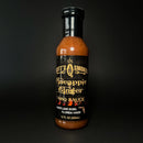 A bottle of Scott’s Smoked Q Pineapple Ginger Sauce Tropical Glaze, Marinade & Dip, 12 fl oz (355 mL), featuring a black label with gold lettering, photographed against a black background. This tropical sauce from Scott’s Smoked Q delivers a sweet and tangy blend ideal for marinating, glazing, or dipping to add bold flavor to your favorite dishes.