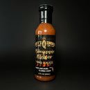 A bottle of Scott’s Smoked Q Pineapple Ginger Sauce Tropical Glaze, Marinade & Dip, 12 fl oz (355 mL), featuring a black label with gold lettering, photographed against a black background. This tropical sauce from Scott’s Smoked Q delivers a sweet and tangy blend ideal for marinating, glazing, or dipping to add bold flavor to your favorite dishes.