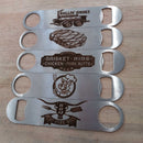 Five DDR BBQ Supply Metal Bottle Openers with engraved BBQ-themed designs—food truck, grilled meat, chef with utensils, and phrases like “Brisket Ribs Chicken Pork Butts” and “BBQ Live Fire Beer”—displayed on wood.