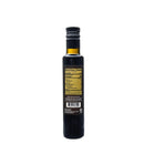A dark glass bottle of Texas Hill Country Olive Co. Bourbon Reserve Balsamic Vinegar with a black cap is shown from the back, featuring its yellow nutrition facts label and barcode against a plain white background.